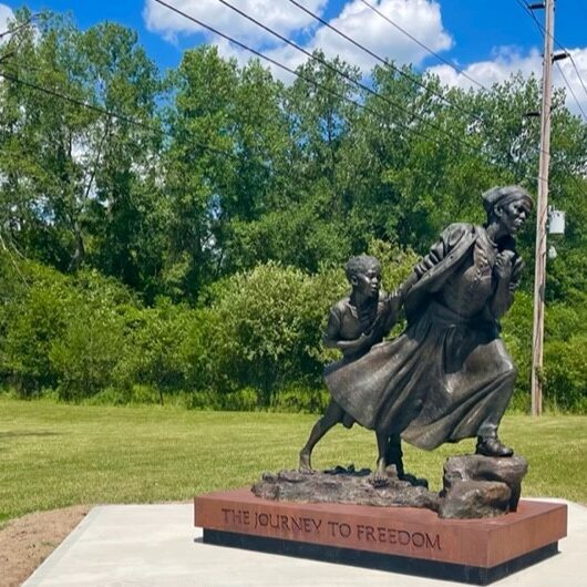 statue of Harriet Tubman and a child in a park with trees in the background