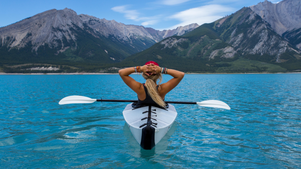 a woman in a kayak looks out over mountains.